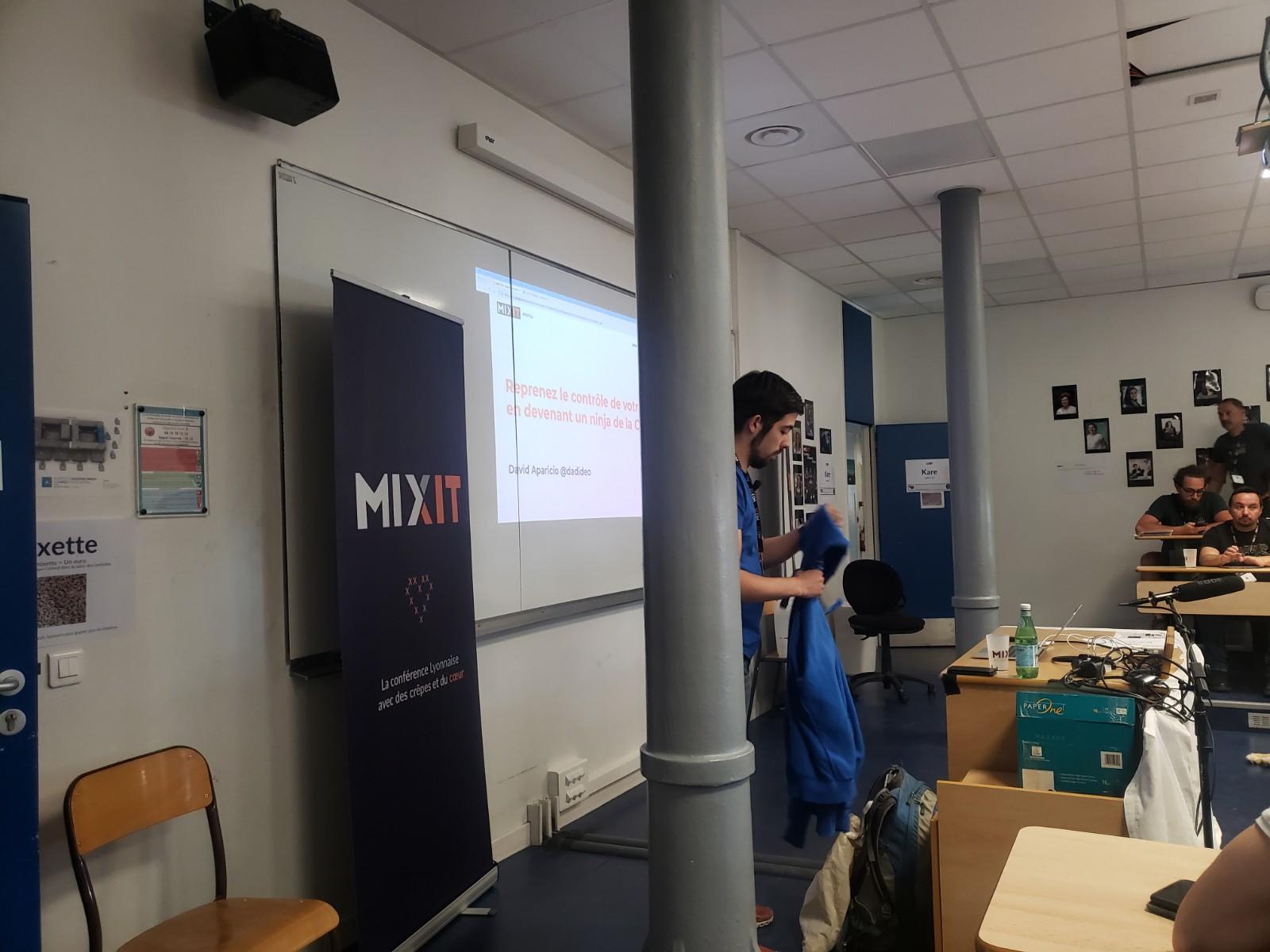 Photo des slides dans une salle de cours, avec un poteau bloquant partiellement la vue sur les slides